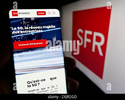 Stoccarda, Germania, 12-07-2023: Persona che detiene il cellulare con pagina web della società francese Societe Francaise du radiophone (SFR) con logo. Foto Stock