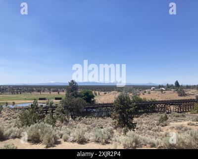 Vista su un ponte di cavalletti al Brasada Ranch, un resort di lusso vicino a Bend, verso le montagne Sisters in Oregon. Foto Stock