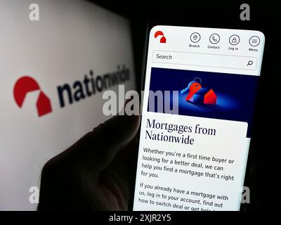 Stoccarda, Germania, 12-14-2023: Persona che detiene il cellulare con pagina web dell'istituto finanziario britannico Nationwide Building Society con logo. Concentrati Foto Stock