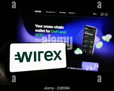 Stoccarda, Germania, 12-18-2023: Persona con smartphone con logo della società fintech croata Wirex Digital d.o.o davanti al sito web. Concentrati su Foto Stock