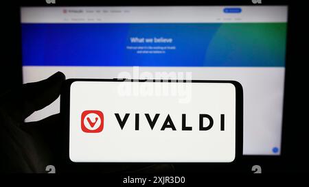 Stoccarda, Germania, 12-18-2023: Persona che detiene uno smartphone con il logo della società norvegese di browser web Vivaldi Technologies COME davanti al sito web. Foto Stock