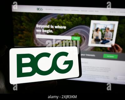 Stoccarda, Germania, 12-20-2023: Persona che detiene un telefono cellulare con il logo della società americana Boston Consulting Group Inc. (BCG) davanti alla pagina web. Foto Stock