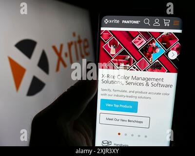 Stoccarda, Germania, 12-28-2023: Persona che tiene il cellulare con pagina web di US color Products X-Rite Inc. Davanti al logo aziendale. Concentrati sul centro di Foto Stock