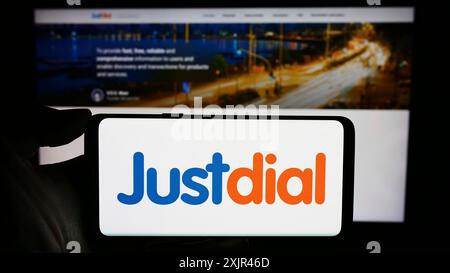 Stoccarda, Germania, 12-31-2023: Persona che tiene il cellulare con il logo della società tecnologica indiana Just Dial Limited (Justdial) di fronte alla pagina web. Foto Stock