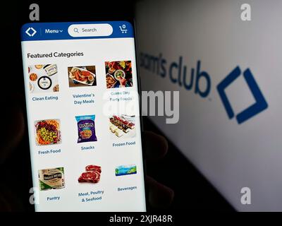 Stuttgart, Germania, 02-07-2023: Persona che detiene un cellulare con pagina web della società di negozi al dettaglio affiliata agli Stati Uniti Sam's Club davanti al logo. Concentrati Foto Stock