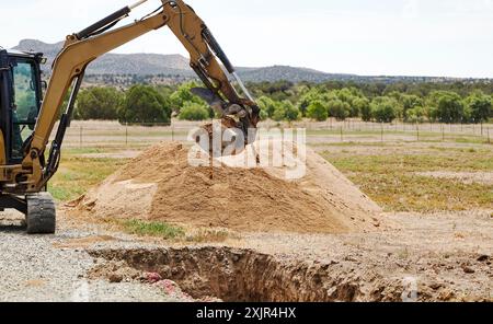Mini benna in acciaio sul braccio di un escavatore che scava fori profondi Foto Stock