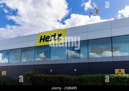 Noleggio auto Hertz all'aeroporto Heathrow di Londra con un aereo che sorvola l'edificio Foto Stock