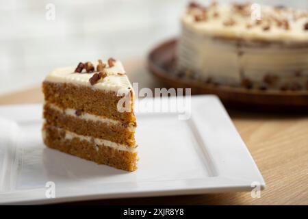 Deliziosa fetta di torta alla carota con glassa al formaggio. Un succulento primo piano di una fetta di torta di carote con ricca glassa di formaggio spalmabile. Foto Stock