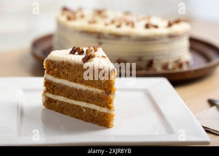 Deliziosa fetta di torta alla carota con glassa al formaggio. Un succulento primo piano di una fetta di torta di carote con ricca glassa di formaggio spalmabile. Foto Stock