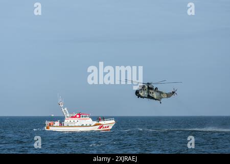 Incrociatore di salvataggio SAR nel Mare del Nord con un elicottero della Marina tedesca che sorvola l'acqua Foto Stock