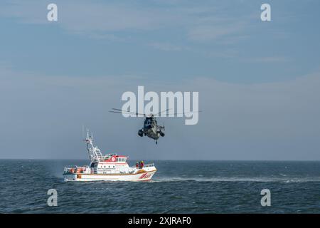 Incrociatore di salvataggio SAR nel Mare del Nord con un elicottero della Marina tedesca che sorvola l'acqua Foto Stock