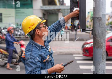 Ho chi Minh City, Vietnam - 21 maggio 2024: Un elettricista fissa un semaforo sulla strada. Foto Stock