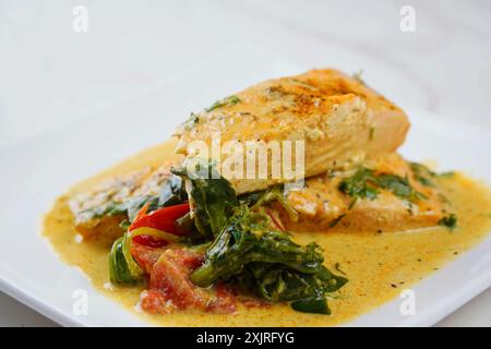 Filetto di salmone con spinaci e pomodori ciliegini in salsa cremosa Foto Stock