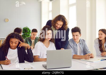 Insegnante che assiste gli studenti adolescenti durante la lezione in aula Foto Stock