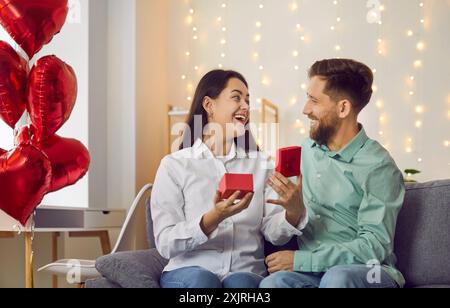 La bella giovane donna è sorpresa di aprire una confezione regalo per San Valentino. Foto Stock