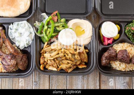 Una vista dall'alto verso il basso di tre combo mediterranee in contenitori da asporto, con griglia di agnello, shawarma di pollo e kabob di manzo. Foto Stock