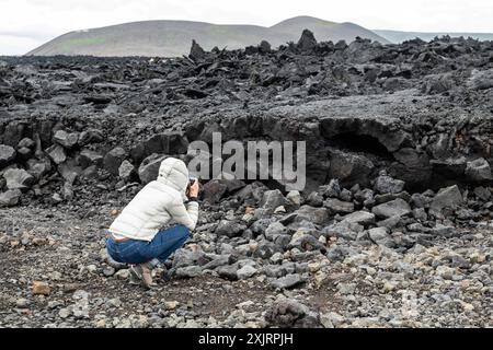 Touristen betrachten die Frisch erstarrte Lava, die beim Ausbruch entlang der Kraterreihe Sundhnúkagígar auf der Reykjanes-Halbinsel im Südwesten Island vor kurzem entstanden ist. Einige Besucher begehen sogar das frische Lavafeld, era sehr gefährlich ist, da die Lava sehr instabil ist und unter der Oberfläche über eine lange Zeit sehr heiß sein kann. DAS Betreten ist daher verboten. / I turisti osservano la lava appena solidificata che ha recentemente eruttato lungo la serie di crateri Sundhnúkagígar sulla penisola di Reykjanes nel sud-ovest dell'Islanda. Alcuni visitatori camminano anche sul campo di lava fresco, che Foto Stock