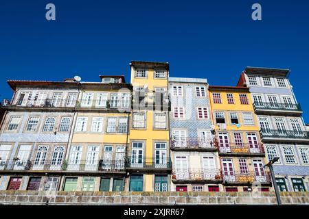 Colorati edifici tradizionali con facciate piastrellate sotto il cielo azzurro. Fila di colorati edifici storici con intricati balconi e piastrelle a motivi geometrici, che si innalzano sotto un cielo azzurro. Gita a Porto in Portogallo. Foto Stock