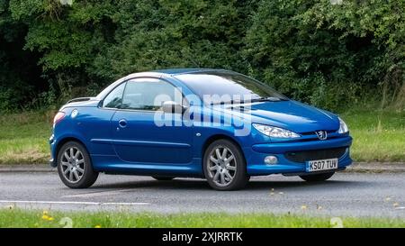 Milton Keynes, Regno Unito - 18 luglio 2024: 2007 Peugeot 206 blu che guida su una strada di campagna britannica Foto Stock