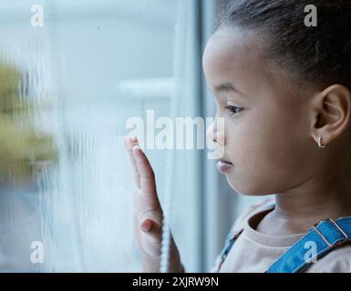 Ansia, ragazza e triste da finestra in casa a affidamento cura per il pensiero, depressione e salute mentale. Piccolo orfano, bambino e solitario con il bicchiere Foto Stock