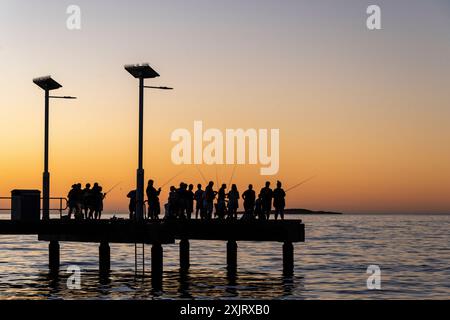 Sagoma della gente che pesca sul molo di Jurien Bay dopo il tramonto. Foto Stock