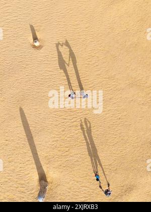 Vista aerea dei bambini che giocano intorno ai pinnacoli, proiettando lunghe ombre alla luce del mattino. Foto Stock