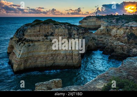 Costa rocciosa di Carvoeiro con il lontano faro di Alfanzina, Portogallo Foto Stock