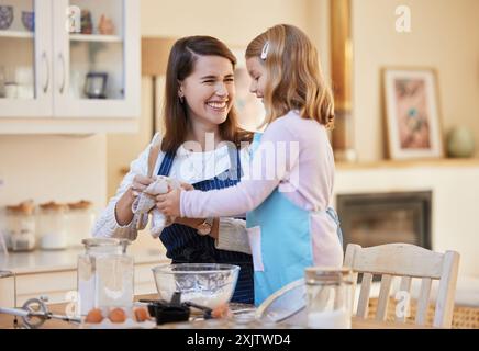 Mamma e figlia felici e pulizie con le mani in cottura per dessert, snack o mescolare gli ingredienti a casa. Bambino o bambina Foto Stock