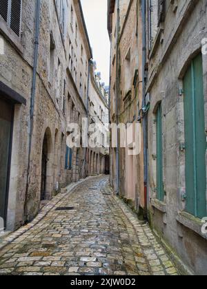 Perigreaux, Francia - 1 maggio 2024: Una strada deserta e stretta con ciottoli bagnati in una giornata di pioggia a Perigreaux, nella regione francese della Dordogna. Foto Stock