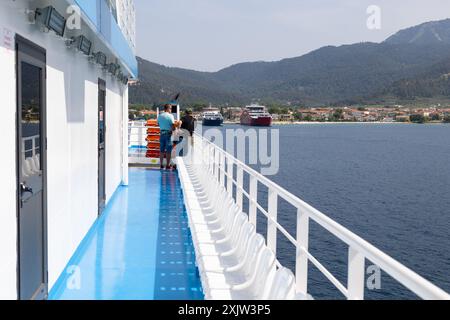 Limenas, Thassos, Grecia - 12 giugno 2024: Le persone viaggiano a bordo, posti bianchi sulla terrazza del traghetto, vista sul porto Foto Stock