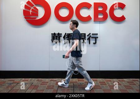 Una passeggiata passeggia davanti alla multinazionale di servizi bancari e finanziari di Singapore, Oversea-Chinese Banking Corporation Limited (OCBC), a Hong Kong. Foto Stock