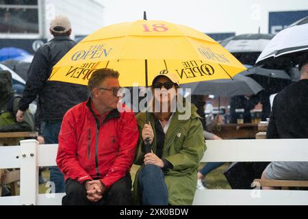 Troon, Scozia, Regno Unito. 20 luglio 2024. Il terzo round del 152° Campionato Open si tiene presso il campo da golf Royal Troon. PIC; gli spettatori si proteggono dalla pioggia sotto l'ombrello. Iain Masterton/Alamy Live News Foto Stock