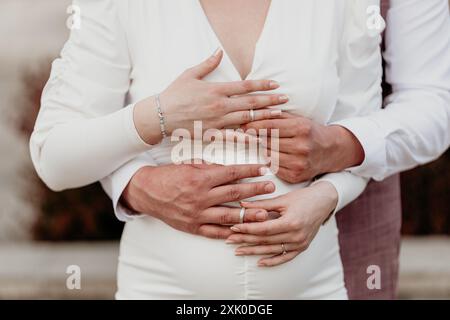 Una coppia appena sposata sta vicino, le loro mani si intrecciano, simboleggiando il loro amore e impegno. Foto Stock