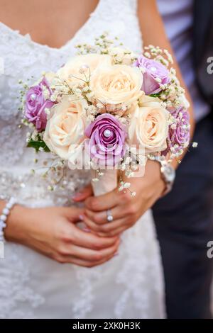 Una sposa regala un bouquet di rose bianche e viola e il respiro del bambino. Foto Stock