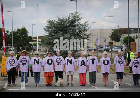 20 luglio 2024, Lakenheath, Inghilterra, Regno Unito: I manifestanti si allineano attraverso la strada di accesso alla base aerea per tenere un silenzio di due minuti per coloro che sono morti a causa di una guerra fuori dalla base aerea di Lakenheath, durante la manifestazione. La protesta è stata organizzata dalla Campaign for Nuclear Disarmament (CND), i cui sostenitori si oppongono al potenziale ritorno di armi nucleari alle basi militari del Regno Unito, come la RAF Lakenheath dopo che è stato riferito che gli Stati Uniti intendono trasferire bombe nucleari alla base. Dopo una lunga protesta le armi nucleari furono rimosse da Lakenheath nel 2008. (Immagine credito: Foto Stock