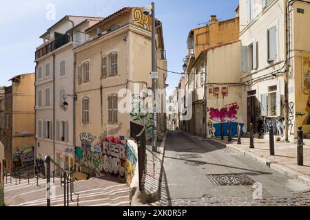 Strada tipica, rue du Poirier, nel quartiere le Panier, Marsiglia, Francia, incrocio di stradine strette con scalini, edifici ricoperti di graffiti. Foto Stock