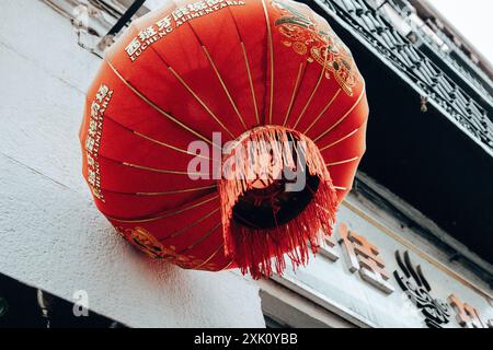 Madrid, Spagna. 1° luglio 2024 carta decorativa rossa lanterna cinese appesa su una facciata di un caffè in una strada della città. Scena urbana. Dettagli sulla cultura cinese. Foto Stock