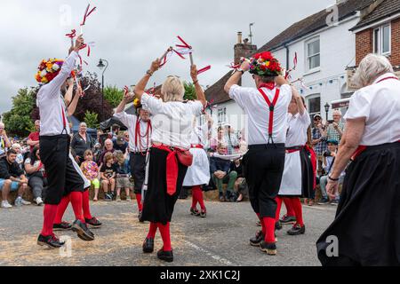 Overton Sheep Fair il 20 luglio 2024. Il tradizionale evento quadriennale si è svolto nel villaggio di Overton, Inghilterra, nel Regno Unito, nell'Hampshire, a partire da una pecora che ha guidato lungo la strada. C'erano molte bancarelle e intrattenimenti, tra cui balli Morris e una varietà di spettacoli di musica dal vivo. Nella foto: I ballerini Basingclog Morris intrattenono la folla nell'arena nel centro del villaggio Foto Stock