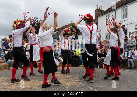 Overton Sheep Fair il 20 luglio 2024. Il tradizionale evento quadriennale si è svolto nel villaggio di Overton, Inghilterra, nel Regno Unito, nell'Hampshire, a partire da una pecora che ha guidato lungo la strada. C'erano molte bancarelle e intrattenimenti, tra cui balli Morris e una varietà di spettacoli di musica dal vivo. Nella foto: I ballerini Basingclog Morris intrattenono la folla nell'arena nel centro del villaggio Foto Stock