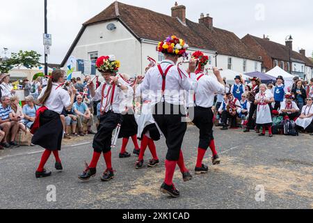 Overton Sheep Fair il 20 luglio 2024. Il tradizionale evento quadriennale si è svolto nel villaggio di Overton, Inghilterra, nel Regno Unito, nell'Hampshire, a partire da una pecora che ha guidato lungo la strada. C'erano molte bancarelle e intrattenimenti, tra cui balli Morris e una varietà di spettacoli di musica dal vivo. Nella foto: I ballerini Basingclog Morris intrattenono la folla nell'arena nel centro del villaggio Foto Stock