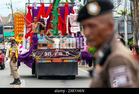 Un ufficiale di polizia tailandese è in guardia durante la processione delle candele per mostrare rispetto e devozione al buddismo e per preservare il loro patrimonio culturale. La tradizione della Candle Parade nel distretto di Mueang chi Sub, nel distretto di Mueang, nella provincia di Lamphun è un evento significativo durante il periodo della Quaresima buddista. Gli abitanti del villaggio si riunirono per creare grandi candele e sfilarle al tempio come atto di devozione e per preservare il loro patrimonio culturale locale. In tali tradizioni, è l'unico nel nord della Thailandia che è stato praticato per decenni. Foto Stock