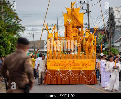 Un ufficiale di polizia tailandese è in guardia durante la processione delle candele per mostrare rispetto e devozione al buddismo e per preservare il loro patrimonio culturale. La tradizione della Candle Parade nel distretto di Mueang chi Sub, nel distretto di Mueang, nella provincia di Lamphun è un evento significativo durante il periodo della Quaresima buddista. Gli abitanti del villaggio si riunirono per creare grandi candele e sfilarle al tempio come atto di devozione e per preservare il loro patrimonio culturale locale. In tali tradizioni, è l'unico nel nord della Thailandia che è stato praticato per decenni. Foto Stock