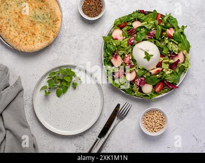 Fotografia gastronomica di insalata con burrata e pesche; mozzarella, formaggio; lattuga, radicchio, foglia, pomodoro; pane tostato; pane all'aglio; origano, pinoli, pep Foto Stock