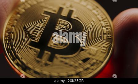 Una persona anonima ha in mano moneta d'oro bitcoin. Criptovaluta elettronica moneta virtuale. Tecnologia moderna Blockchain. Trading di criptovalute P2P bitcoin. Logo BTC. Affari e investimenti. Primo piano. Foto Stock