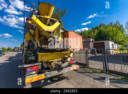Una grande betoniera nera e gialla mescola e versa cemento mentre costruisce le fondamenta di una casa Foto Stock