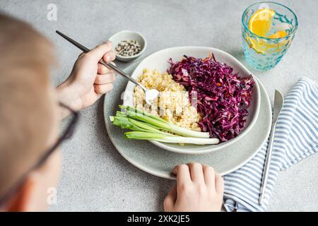 Una ciotola di cibo sano con un colorato cavolo rosso crudo e insalata di carote accanto al soffice bulgur bollito, servito con cipolle verdi fresche Foto Stock