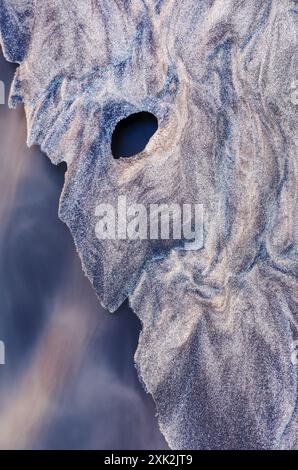 Catturata a Lofoten, questa immagine mostra gli intricati motivi di gelo che si formano su una spiaggia sabbiosa, somiglianti a un viso etereo, offrendo un'incredibile esposizione Foto Stock