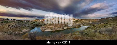 Una vista panoramica mozzafiato che cattura Toledo, Castilla la Mancha, situata contro un cielo drammatico e lunare, l'architettura storica e il fiume sereno Foto Stock