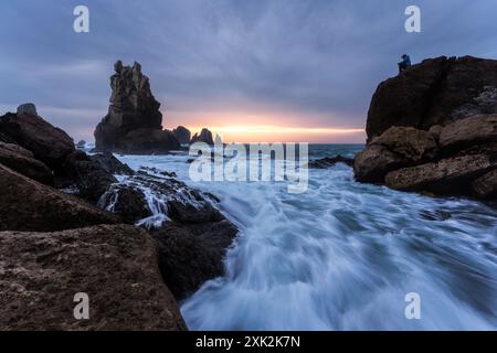 Una vista ipnotizzante della Costa Quebrada in Cantabria, con le onde che si infrangono attorno alle rocce aspre sotto uno spettacolare tramonto. Con un anonimo Foto Stock