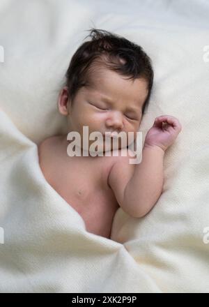 Ritratto di un bambino appena nato sotto una coperta bianca. Primo piano Foto Stock